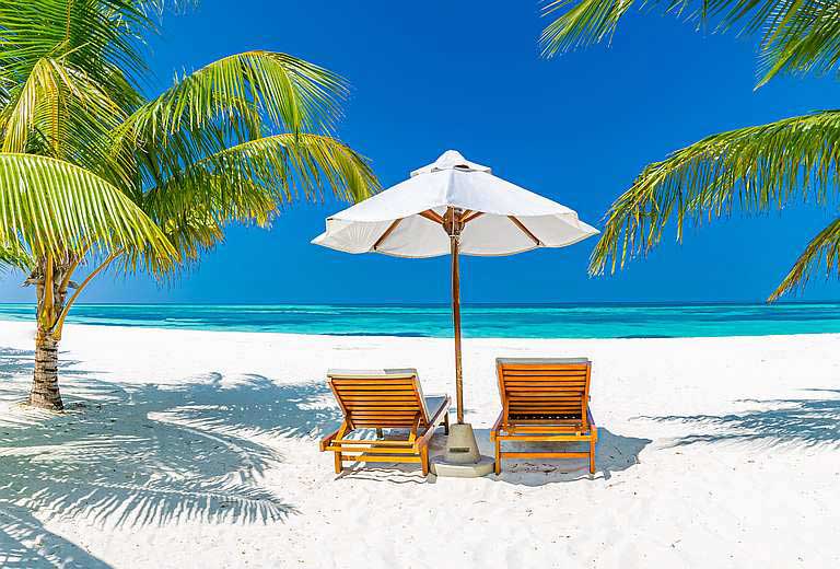 Zwei Strandliegen mit Sonnenschirm am Karibik-Strand